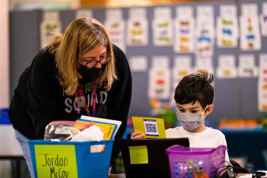 Image of teacher helping student at desk